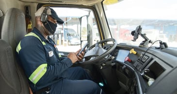 driver in cab of truck on his phone using an app